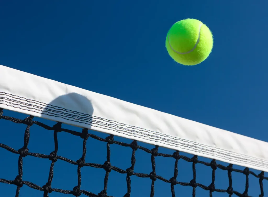 tennis ball flying over a tennis court net